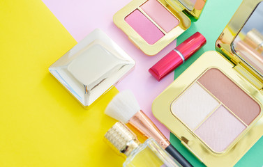 premium makeup brushes, red lipstick, bottle of perfume and blush pads on a bright colorful background, creative cosmetics flat lay