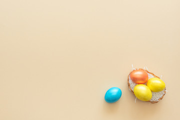 Decorated Easter eggs lie in the basket like a nest on yellow background. Happy Easter holiday concept. Greeting, invitation card. Flat lay style with copy space.