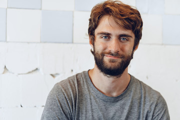 Close up Portrait of a young bearded man standing against grunge weathered wall