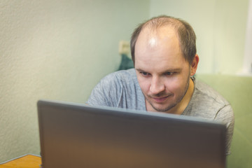 concentrated young man while using his laptop at home/focused young man working behind a laptop at home