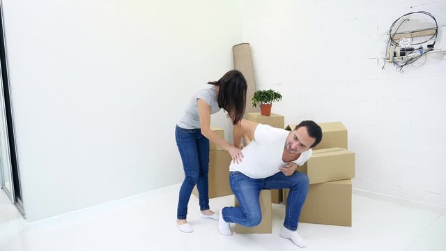 Man has lower back pain injury from heavy lifting during removal into new flat, his wife tries to help him.