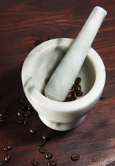 Pestle and mortar on dark wood background, top view, with coffee beans