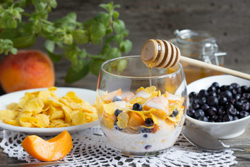 Cornflakes with peaches, blueberries and honey. Healthy breakfast with vitamins.