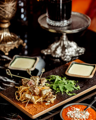lamb steak pieces on stick served with shoestrings arugula and sauce