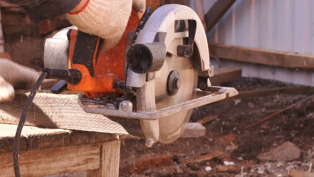 The circular saw in process. The carpenter cuts the edges of a large piece of wood . Carpenter's workshop