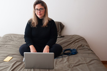 happy woman using the computer in her bedroom