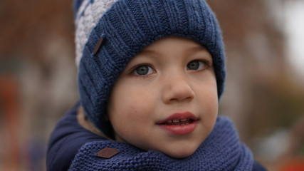 Close-up portrait of little cute boy in a blue knitted hat