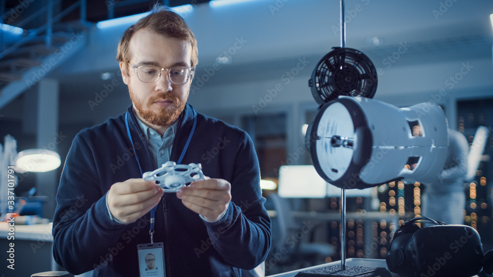 Poster electronics development engineer working at his desk, fits new technological component into prototyp