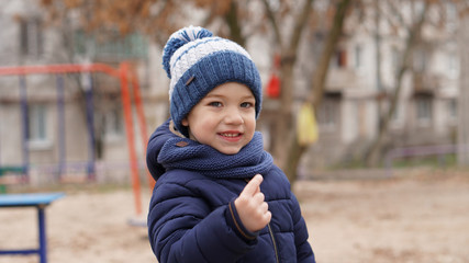 Portrait of little cute boy in a white-blue knitted hat with pompom