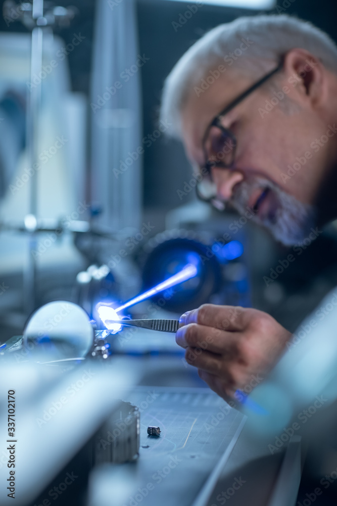Aufkleber portrait of focused middle aged engineer in glasses working with high precision laser equipment, usi