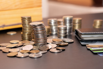 Money, Finance, business growth concept,several stacks of coins and credit cards on a black wooden table against a wooden piggy Bank.