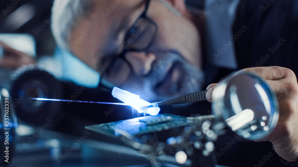 Aufkleber Close-up Portrait of Focused Middle Aged Engineer in Glasses Working with High Precision Laser Equipment, Using Lenses and Optics for Accuracy Electronics. Testing Superconductor Material 