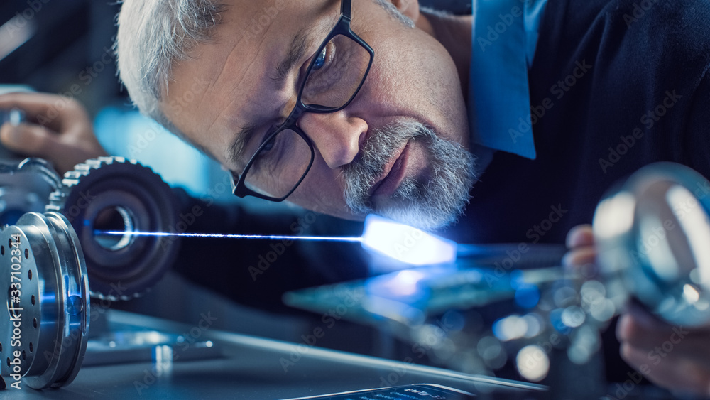 Poster Close-up Portrait of Focused Middle Aged Engineer in Glasses Working with High Precision Laser Equipment, Using Lenses and Optics for Accuracy Electronics. Testing Superconductor Material 