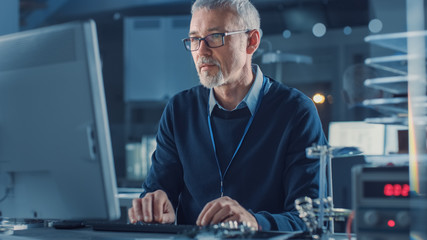 Middle Aged Electronics Repair Engineer Working on Personal Computer in His Workshop, Checks...