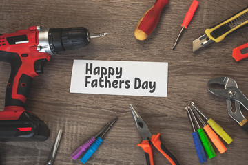 happy fathers day inscription in the center of a wooden table surrounded by tools
