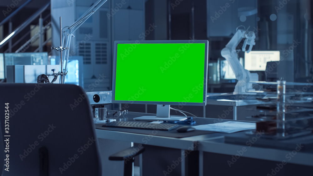 Poster on the desk computer with isolated green mock-up screen display. in the background robot arm concept