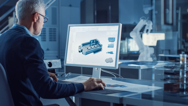 Professional Heavy Industry Engineer Works on Computer Uses CAD Software to Design 3D Industrial Machinery Component. In the Background Robot Arm Concept. Over the Shoulder Shot