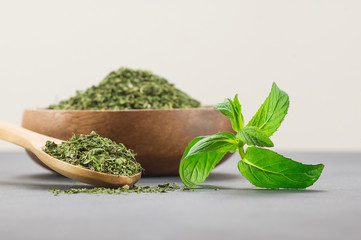 Fresh green peppermint leaves and dried mint leaves in wooden spoon on rustic table. Dry spice concept © mescioglu