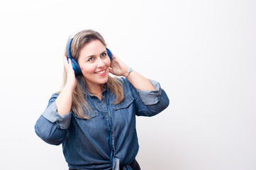 happy blonde woman listening to music with her hands on the headphone