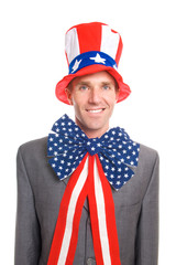 Portrait of patriotic American businessman wearing stars and stripes hat and flag bow standing...