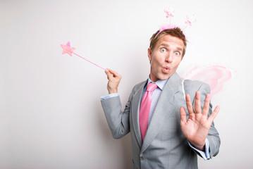 Fairy businessman waving a pink glittery star magic wand granting a wish with a funny expression on his face