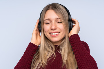 Young blonde woman over isolated blue background listening music