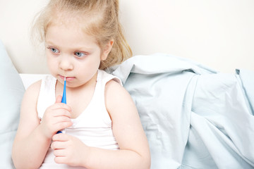 A girl with a high temperature measures the temperature with a thermometer. On sick leave is at home.