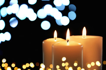 Burning candles on dark background, bokeh effect