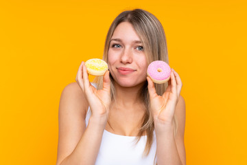 Young blonde woman over isolated blue background holding donuts
