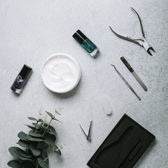 Nail polish, manicure tools and hand cream on grey concrete table top flat lay. How to do manicure at home concept. Do manicure by yourself while staying at home during quarantine, staying safe