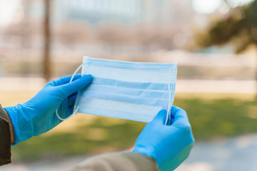 Women holds blue medical mask in medical gloves to stop from epidemy of coronavirus covid 19. Life after long quarantine in Spain