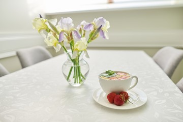 Strawberry tea on table, with vase of irises flowers