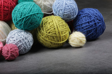 A lot of multi-colored yarn balls on the dark background. Knitting yarn close-up. Knitting is needlework and creativity. Copy space.