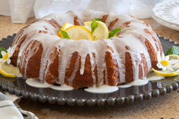 Lemon Ricotta Bundt Cake with icing displayed on a black decorative plate in a light bright airy setting.