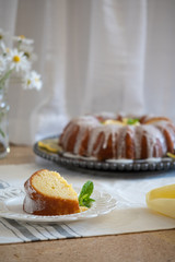 Lemon Ricotta Bundt Cake with icing displayed on a black decorative plate in a light bright airy setting.