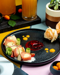 salmon wrap slices filled with cream served with cucumber rolls in unique decorated plate