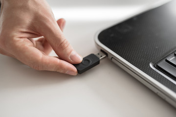 a man plugs a USB flash drive into a laptop with his hand