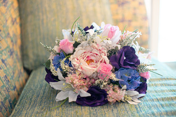 Pink, blue, white, purple silk flowers bridal bouquet on colorful chair