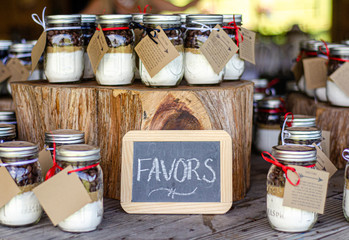 Small chalk board sign that reads"Favors" on party favors table containing mason jars with cookie mix