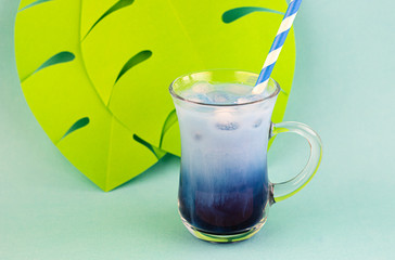 Blue matcha tea with milk and ice cubes in a glass of latte on an exotic background