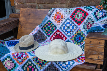 Fototapeta premium a nice pair of hats and a handmade colorful blanket on a bench in the garden