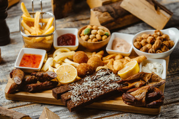 snacks platter with smoked wings sausages french fries nuts and sauces