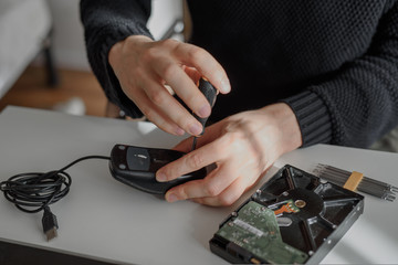 repairman repairing a computer mouse in a workshop at a white table. He unscrews the screws with a...