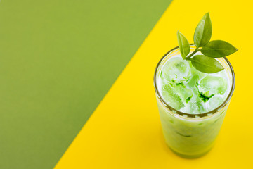 Green matcha tea with milk and ice cubes in a glass of latte on an exotic background
