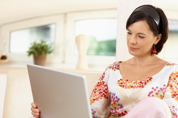 Portrait of young woman tele working with laptop at home office, concentrating.