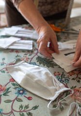 Seamstress making protective masks at home. Top view of handmade medical face mask and process to make one.