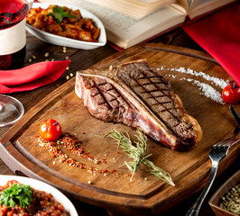 t-bone steak served in wooden board with slat rosemarine