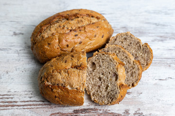 Top view of two fresh healthy loaves of multi-grain seedy bread on rustic wooden table. Homemade sliced and whole loaves of bread close-up. Baking and home bread making background and concept