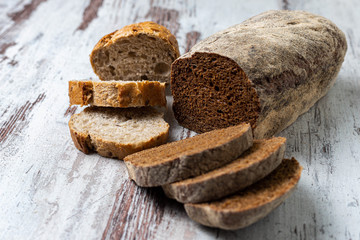Top view of freshly baked healthy sliced small multi-grain seedy and rye bread on rustic wooden table. Assorted loaves of homemade bread. Close-up. Baking recipe, concept, idea, background