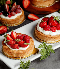 two small pies decorated with cream strawberry and raspberries